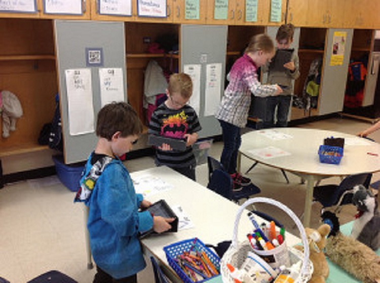 Children standing while using technology in the classroom.